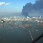 An aerial view of the Sendai region with black smoke coming from the Nippon Oil refinery